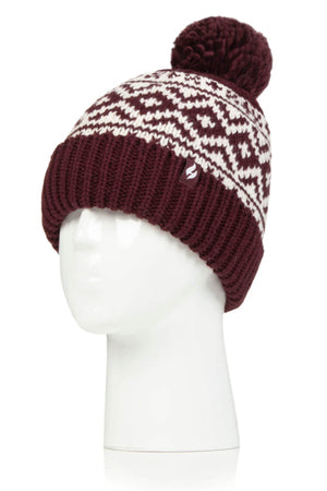Displayed on a white mannequin head is the Heat Holders Aspen Pom Pom Turn Over Ladies Thermal Beanie in maroon and white, featuring a geometric pattern. This stylish beanie boasts a large pom-pom on top and a ribbed, folded brim, making it perfect for those seeking both style and warmth.