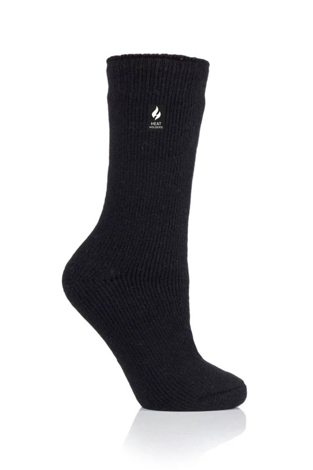 A single black Heat Holders Ladies Original Thermal Heat Sock with a ribbed design and a small flame icon bearing the word "HEAT" printed below it, displayed against a white background. The warm crew-length sock is positioned upright, with the heel and toe visible.