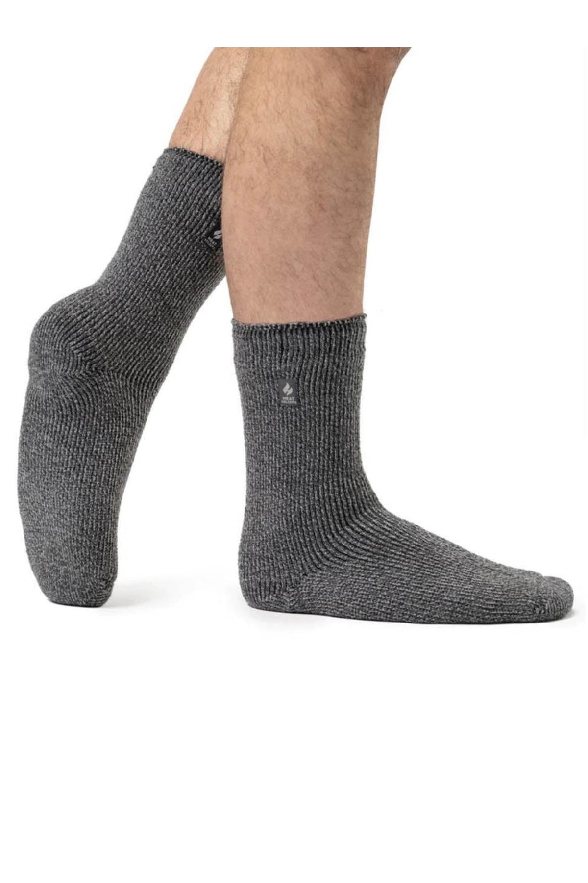 A pair of feet in gray, mid-calf knit socks, like Heat Holders Mens Wool Sock, provides superior warmth. One foot is flat while the other is raised on its toes, perfect for outdoor use against a plain white background.