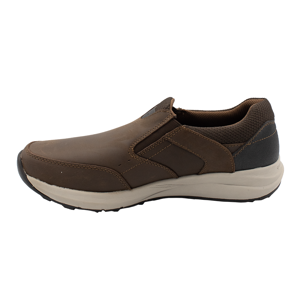 The Florsheim Excursion Slip On is a brown leather shoe featuring a white sole with shock absorption, a textured black heel area, and visible stitching for comfort and durability. The shoe's design ensures every step is easy, being positioned facing left.