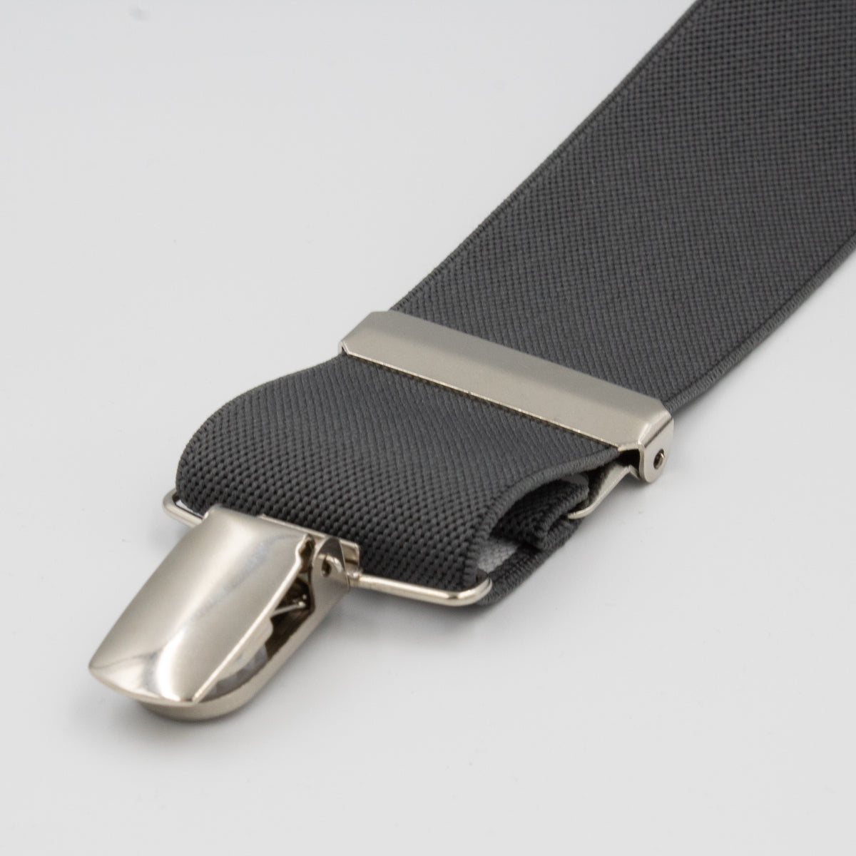 A close-up of Buckle Plain Braces in gray fabric, featuring adjustable straps with a shiny silver metal clip and adjustment piece, displayed on a plain white background.