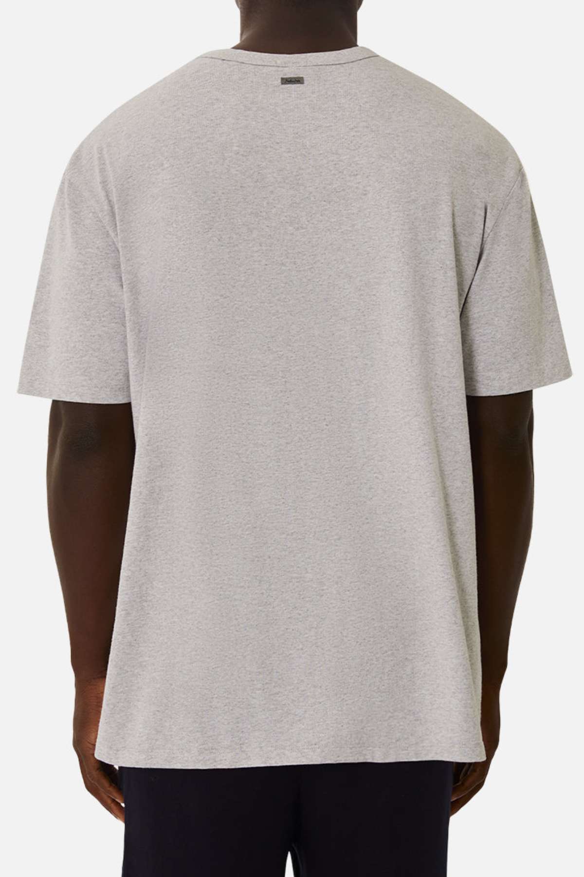 A person is seen from the back wearing an Industrie The Del Sur Tee—an oversized, short-sleeve, 100% cotton shirt—paired with dark pants against a plain white background.