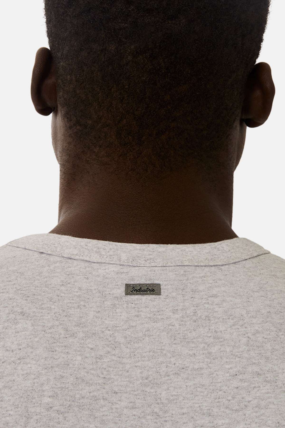 A person with short hair is seen from behind, wearing the Industrie The Del Sur Tee in light gray, featuring a small rectangular “Industrie” label sewn below the neckline.