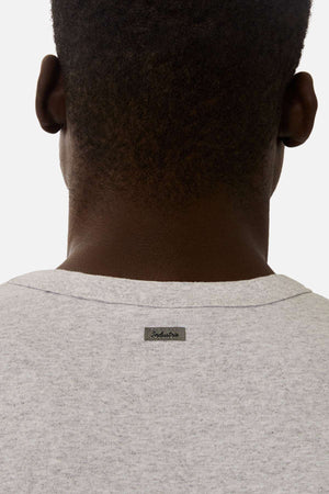 A person with short hair is seen from behind, wearing the Industrie The Del Sur Tee in light gray, featuring a small rectangular “Industrie” label sewn below the neckline.