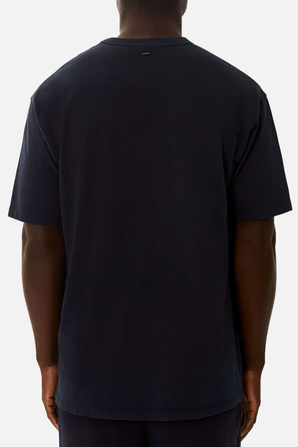 A person is shown from the back wearing the Industrie The Del Sur Tee, an oversized black 100% cotton short-sleeve shirt, standing against a light gray background.