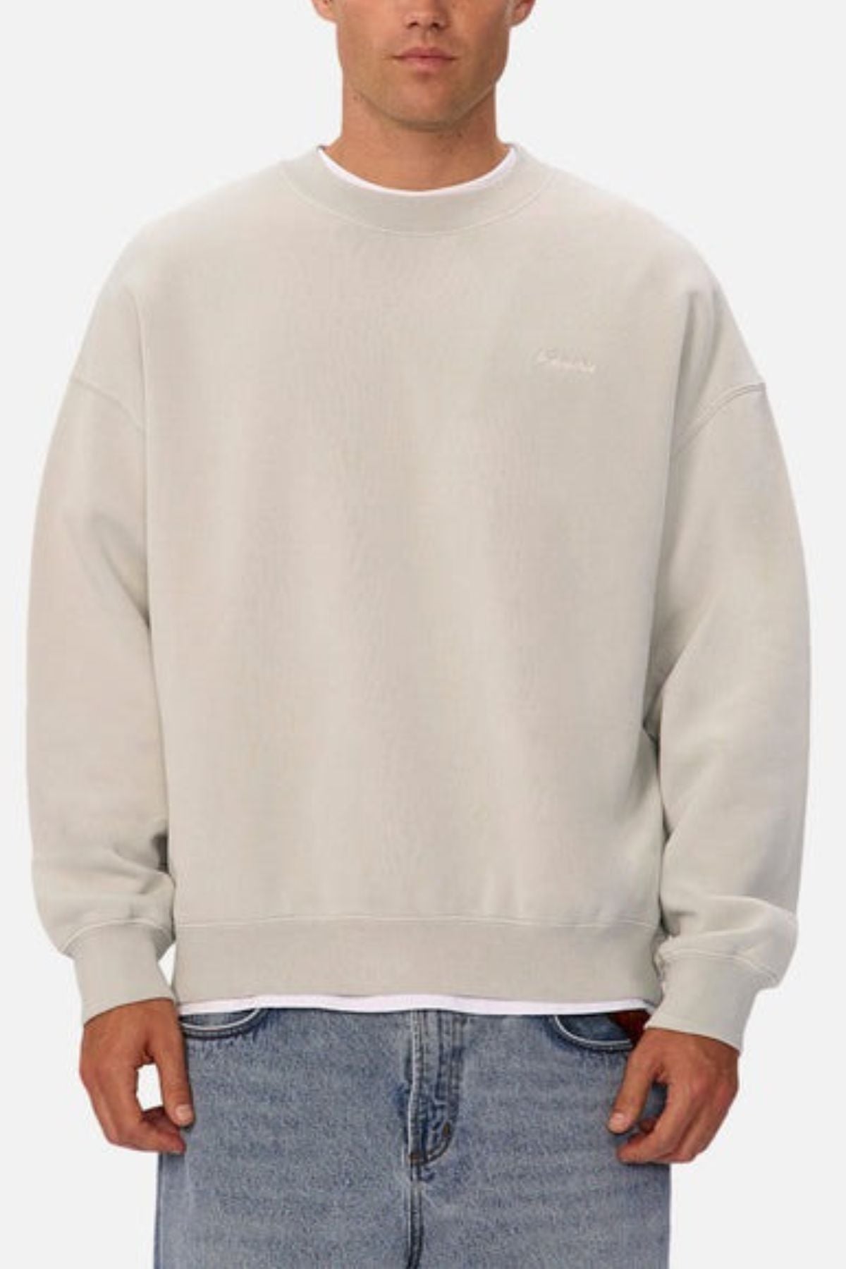Wearing the Industrie The New Del Sur Washed Sweat with an oversized fit over a white shirt and blue jeans, a person stands against a plain white background.