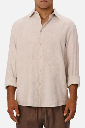 A person wearing the Industrie The St Martins Shirt, a lightweight beige linen top with rolled-up sleeves, paired with brown pants, shown from the waist up against a plain background.