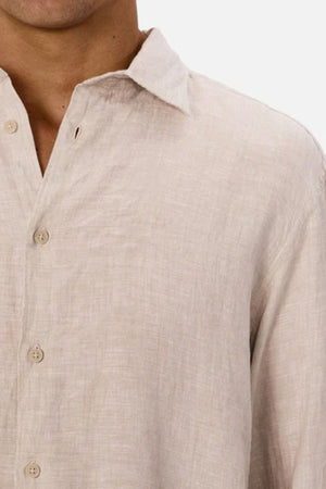 A close-up of a person wearing the Industrie The St Martins Shirt, a light beige, lightweight linen shirt with a collar, showing the upper chest and part of the neck against a plain background.