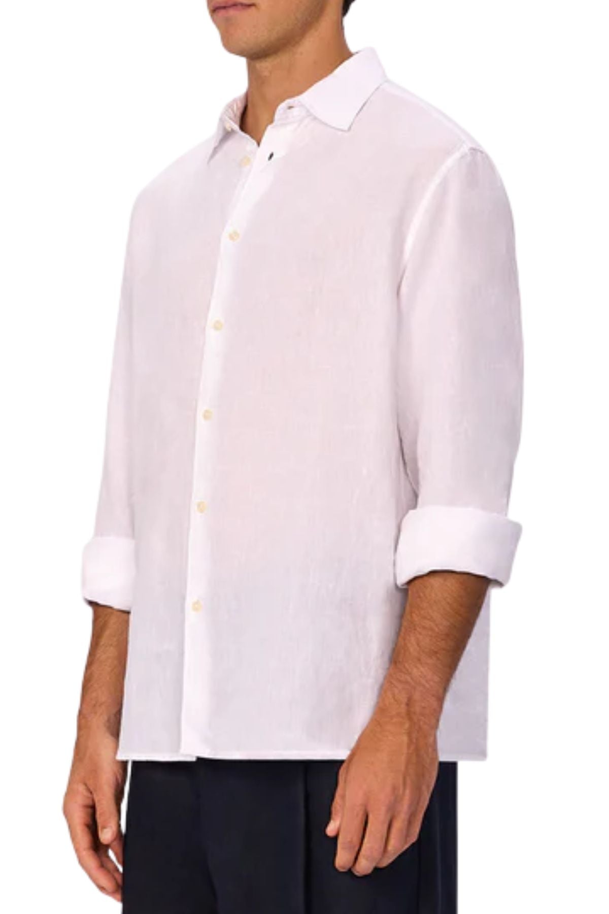 A man wearing the Industrie The St Martins Shirt, a regular fit long-sleeve white linen shirt with rolled-up sleeves, paired with dark pants, stands against a plain white background.
