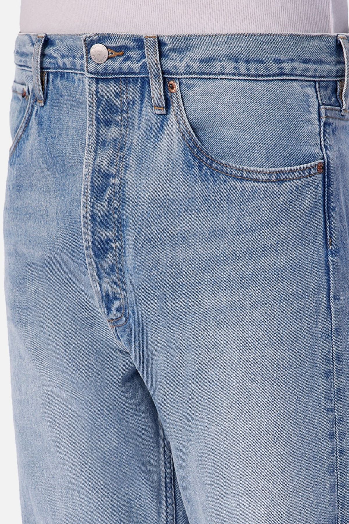 Close-up view of a person wearing Industrie The 90's Jean with a relaxed straight leg fit and vintage wash, styled with a light-colored shirt tucked in, showing the front pocket, waistband, and upper thigh area.