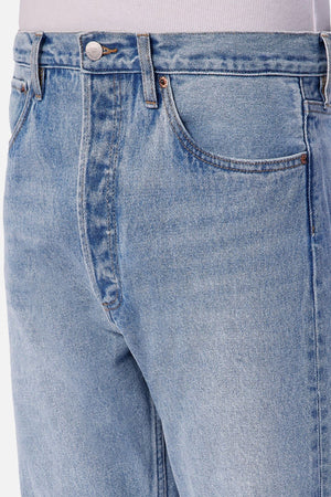 Close-up view of a person wearing Industrie The 90's Jean with a relaxed straight leg fit and vintage wash, styled with a light-colored shirt tucked in, showing the front pocket, waistband, and upper thigh area.