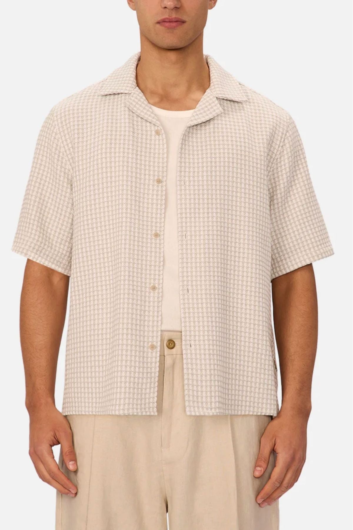 A man wears the Industrie The Almeria Short Sleeve Shirt in light beige over a white T-shirt, paired with beige trousers, standing facing forward against a plain background.