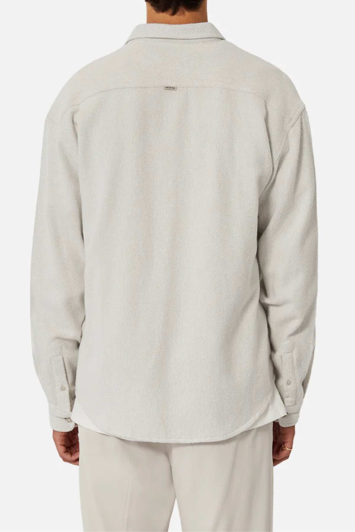 A person is shown from the back against a plain white background, wearing Industrie The Atacama Shirt—a light beige, 100% cotton long-sleeve button-up—paired with matching pants.