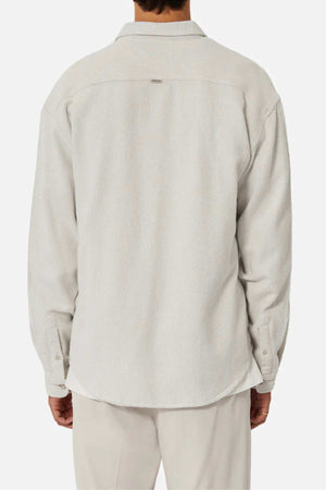 A person is shown from the back against a plain white background, wearing Industrie The Atacama Shirt—a light beige, 100% cotton long-sleeve button-up—paired with matching pants.