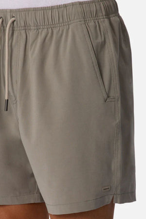 Close-up of a person wearing Industrie The Barbados Swim Short in light gray, featuring side pockets, a fabric logo tag near the hem, quick-dry material, and a cropped fit at the waist and mid-thigh.