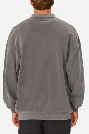 A person is seen from the back wearing the Industrie The Burbank Polo Track in loose, faded gray with black pants against a plain white background.