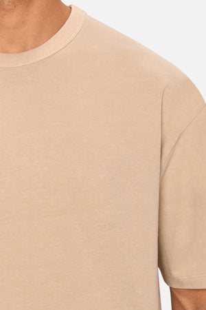 A close-up of someone wearing the Industrie The Del Sur Tee, an oversized beige shirt, highlighting the upper chest, shoulder, and neck.