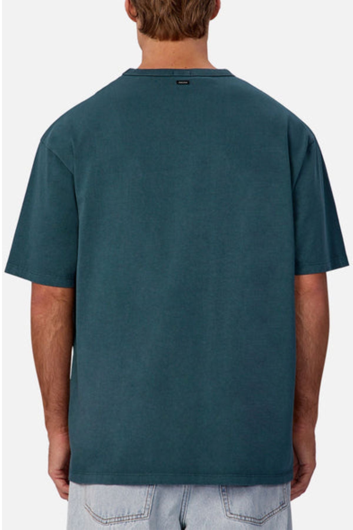 A person is shown from the back wearing an oversized Industrie The Del Sur Tee in plain teal with light blue denim shorts. The heavyweight cotton t-shirt stands out against the simple white background.