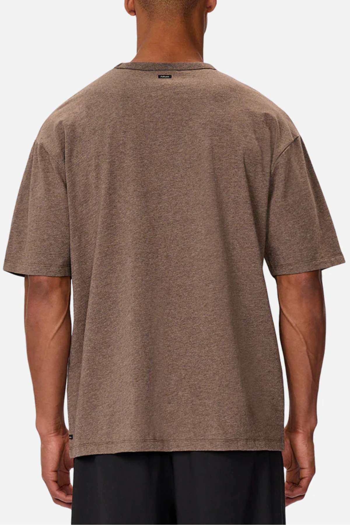 A person in an Industrie The Del Sur Tee, plain brown, stands with their back to the camera against a white background. The heavyweight fabric offers sturdiness, and a black tag near the neckline adds a subtle detail.