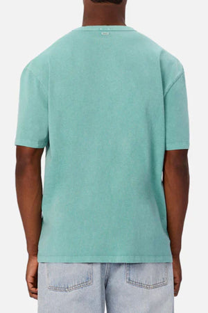 A person is shown from behind wearing an Industrie The Del Sur Tee in plain teal and light blue jeans, standing against a light gray background.