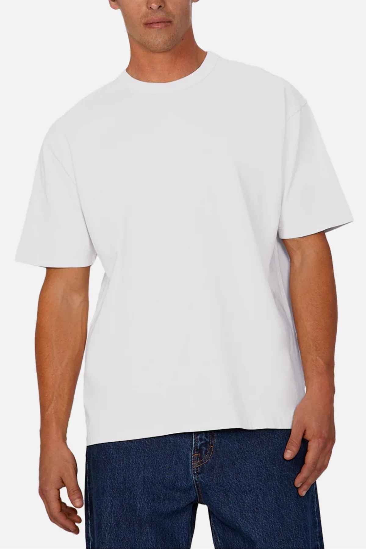 A man is wearing the Industrie The Del Sur Tee in an oversized fit along with blue jeans, standing against a crisp white background.