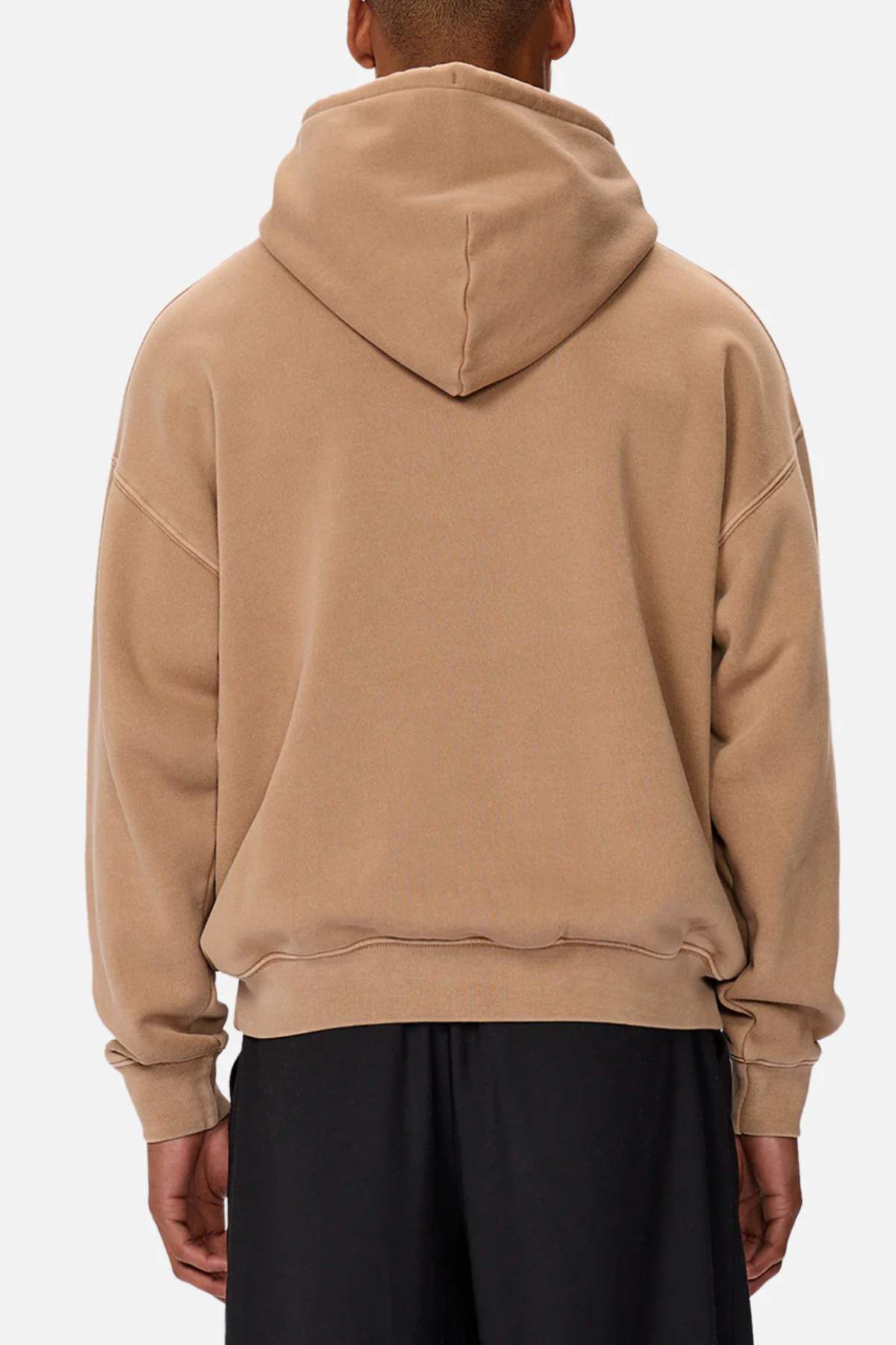 A person wearing the Industrie The Del Sur Washed Hoodie in tan and black pants, viewed from behind. The oversized fit features a large hood and dropped shoulders, enhancing its relaxed vibe against a plain white background.
