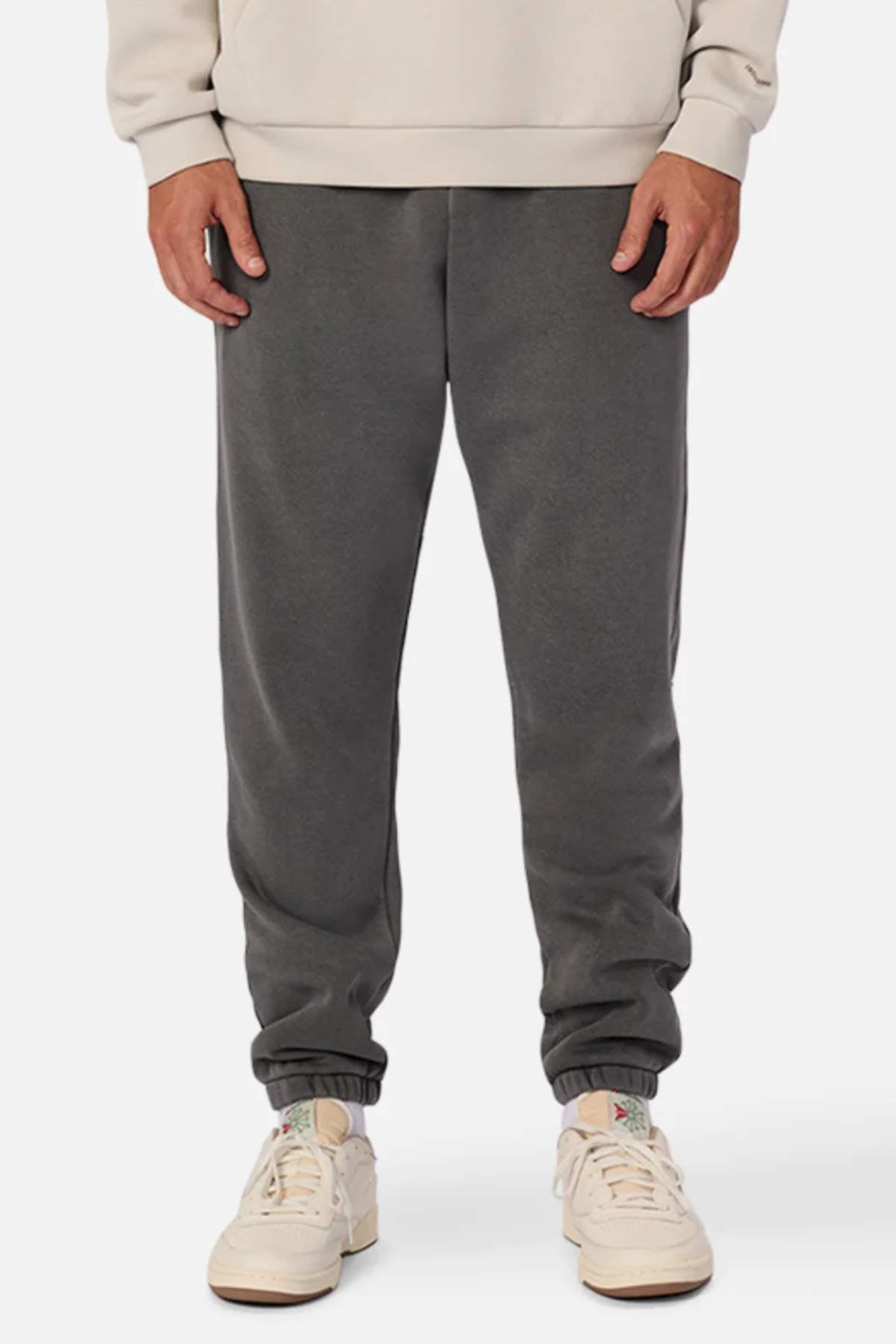 A person wearing a beige sweatshirt, Industrie The Del Sur Washed Track Pant with an elasticated drawstring waist, and white sneakers stands facing forward. Only the body from shoulders down is visible, with hands relaxed at the sides.