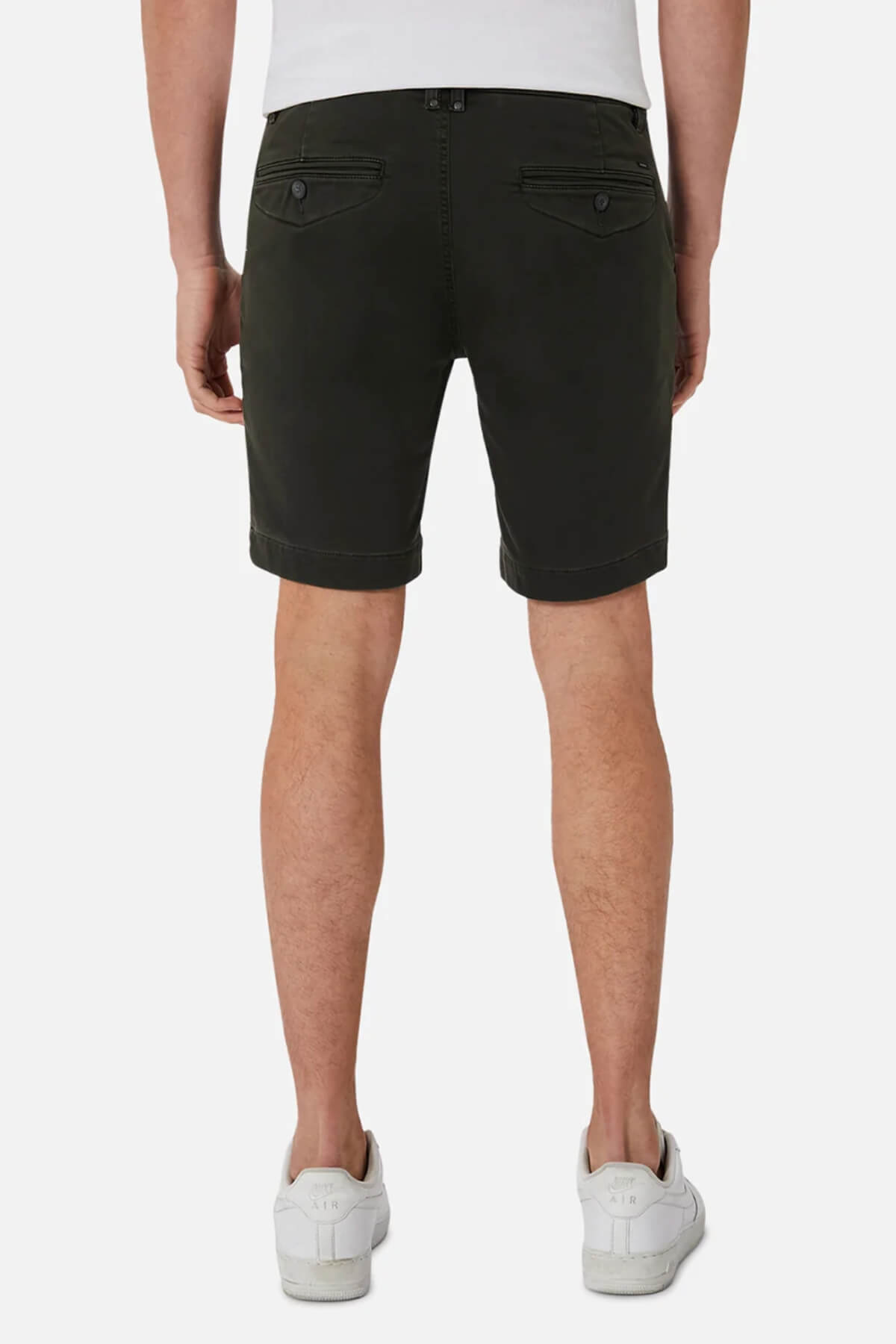 A person is seen from behind wearing Industrie The Drifter Cuba Short in dark green with buttoned pockets, paired with a white shirt and white sneakers, creating a stylish look against the plain white background.