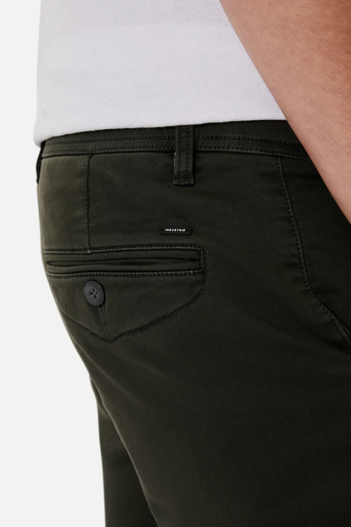 Close-up of a person wearing dark green Industrie The Drifter Cuba Shorts and a white shirt, exuding style. The image highlights the back pocket area, featuring a buttoned pocket and a small Industrie logo label.