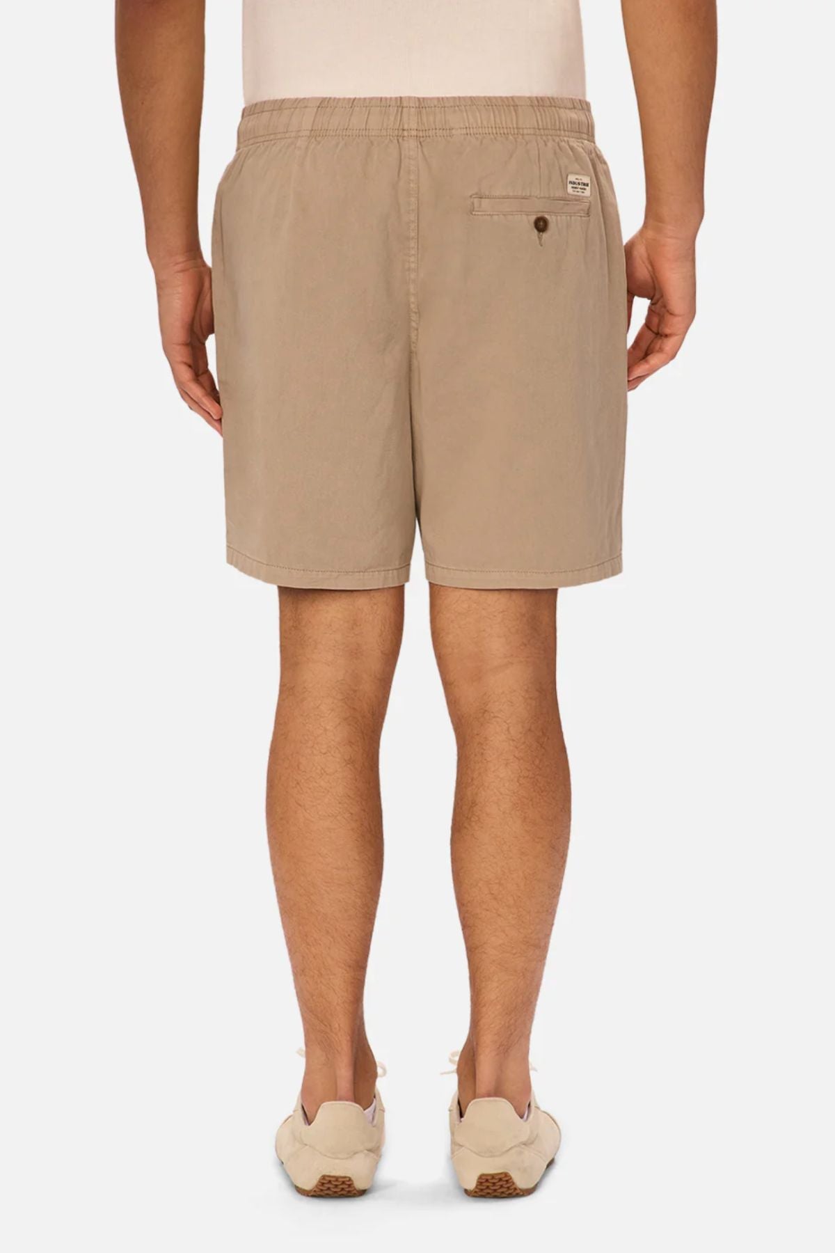 A person is standing facing away on a white background, wearing a white shirt, beige sneakers, and Industrie The Dublin Short—versatile summer shorts with an elastic waistband and back pocket.