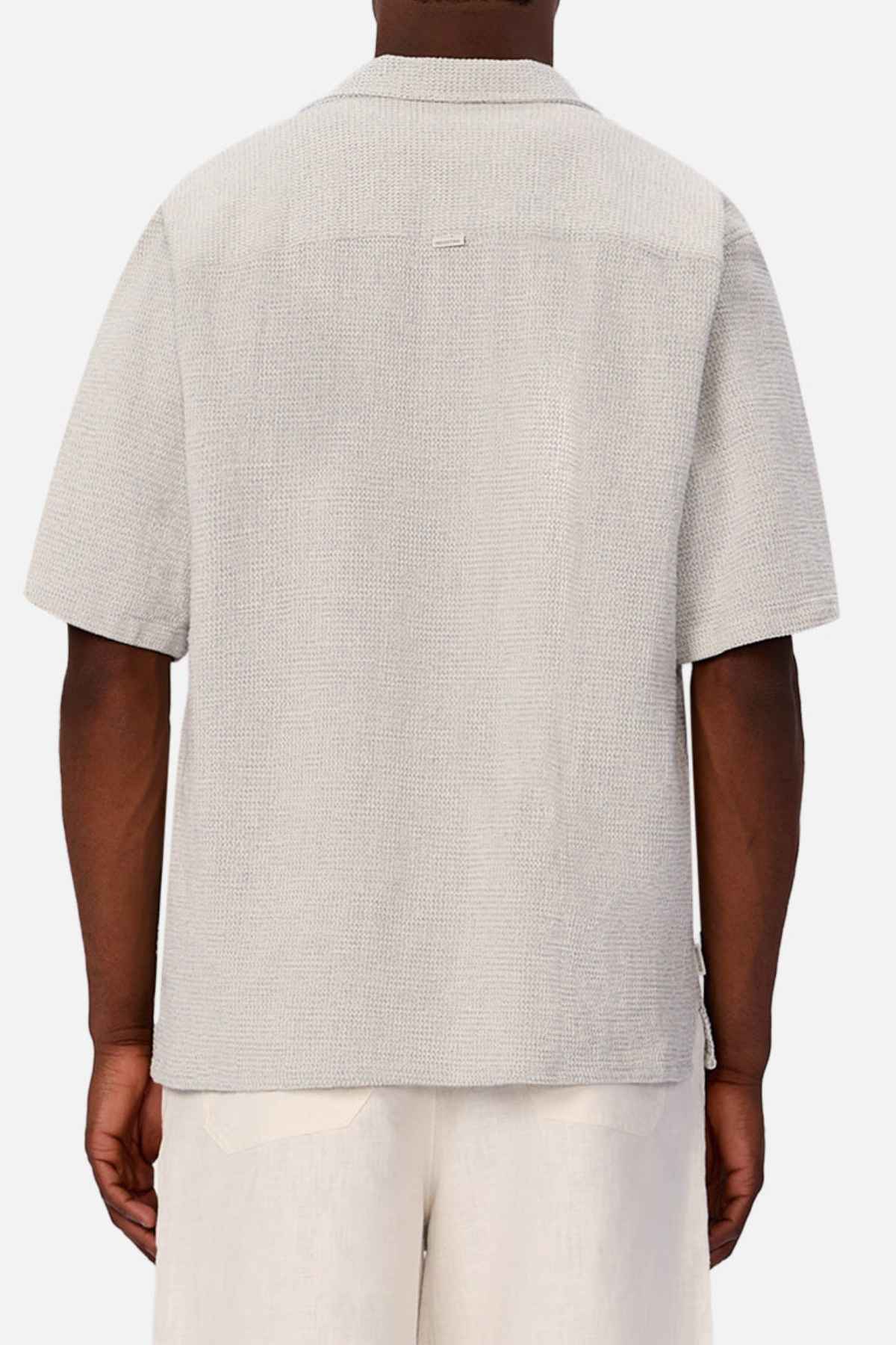 A person is seen from behind wearing a light gray Industrie The Franklin Short Sleeve Shirt and light-colored pants against a plain background.
