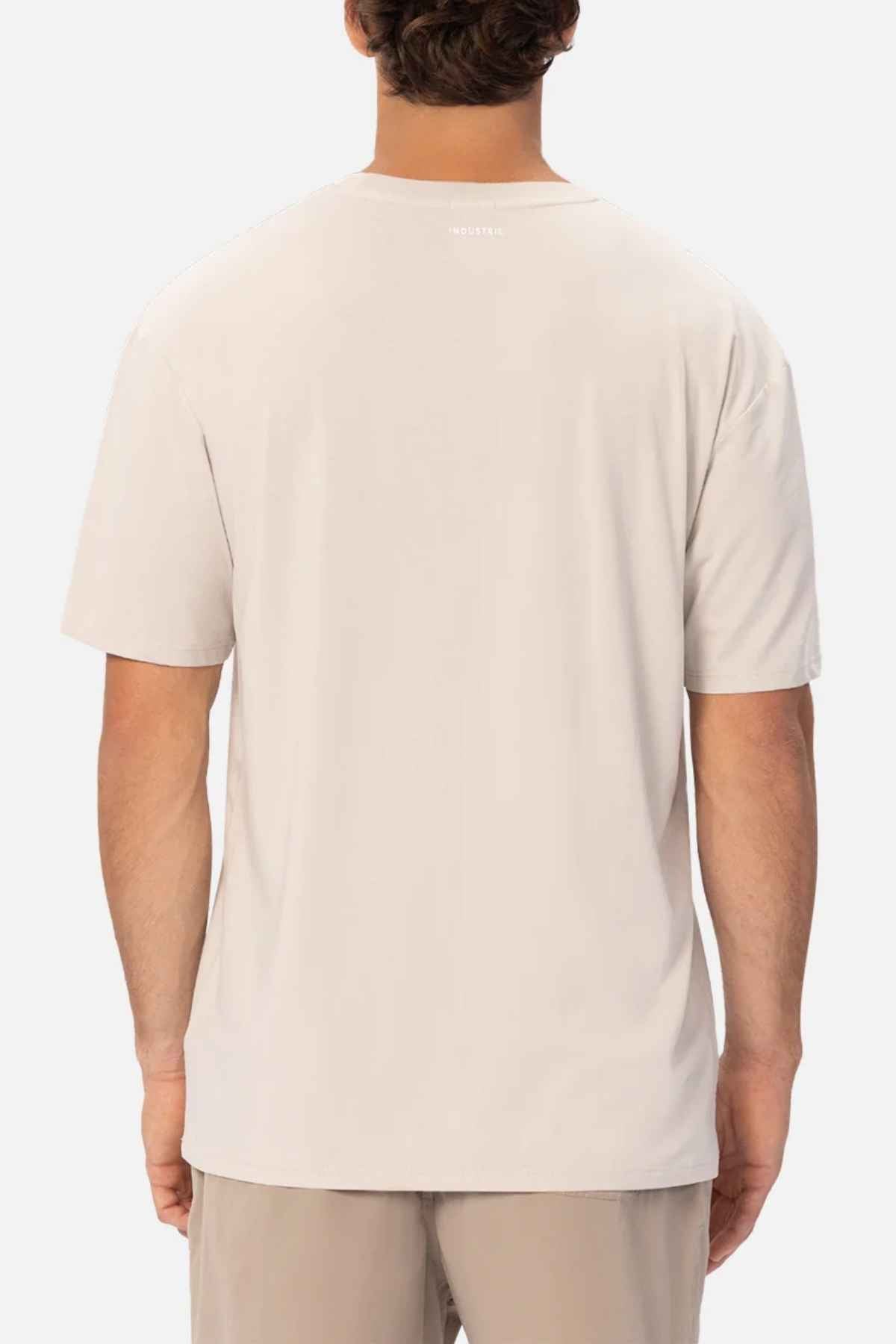 A man wearing a plain beige Industrie The Freeman Athletic Tee and athletic shorts is seen from behind against a white background.