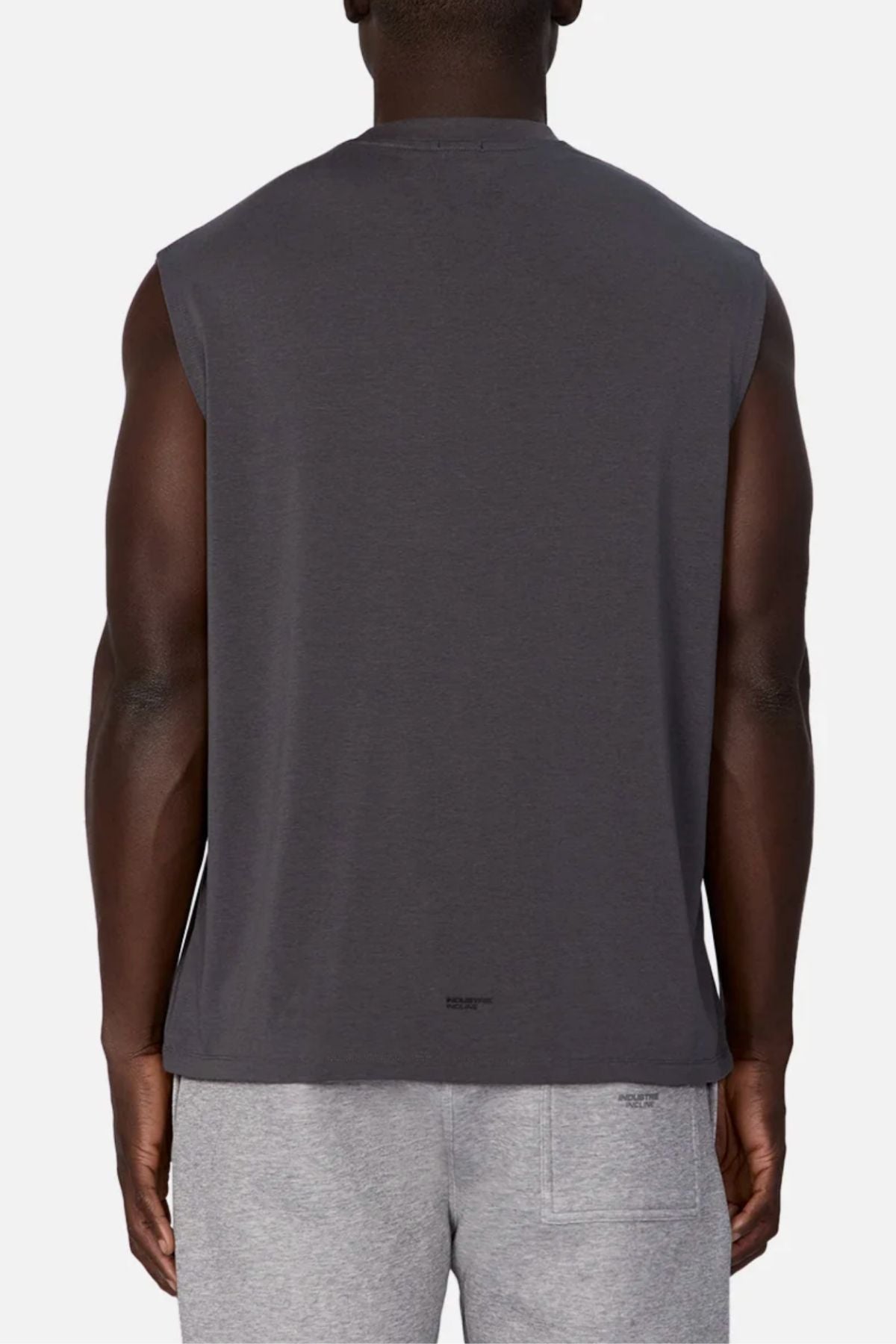 A person is shown from the back wearing the Industrie The Freeman Sleeveless Tee in dark gray, paired with light gray shorts, standing against a plain white background.