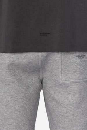 A person wears the Industrie The Freeman Sleeveless Tee in dark gray and light gray sweatpants with a back pocket, quick-dry fabric, and a visible wet stain on the left side, shown from waist to mid-thigh.