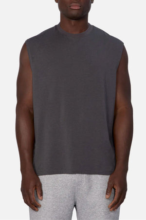 A person wearing the Industrie The Freeman Sleeveless Tee in dark gray and light gray sweatpants stands facing forward against a plain white background.