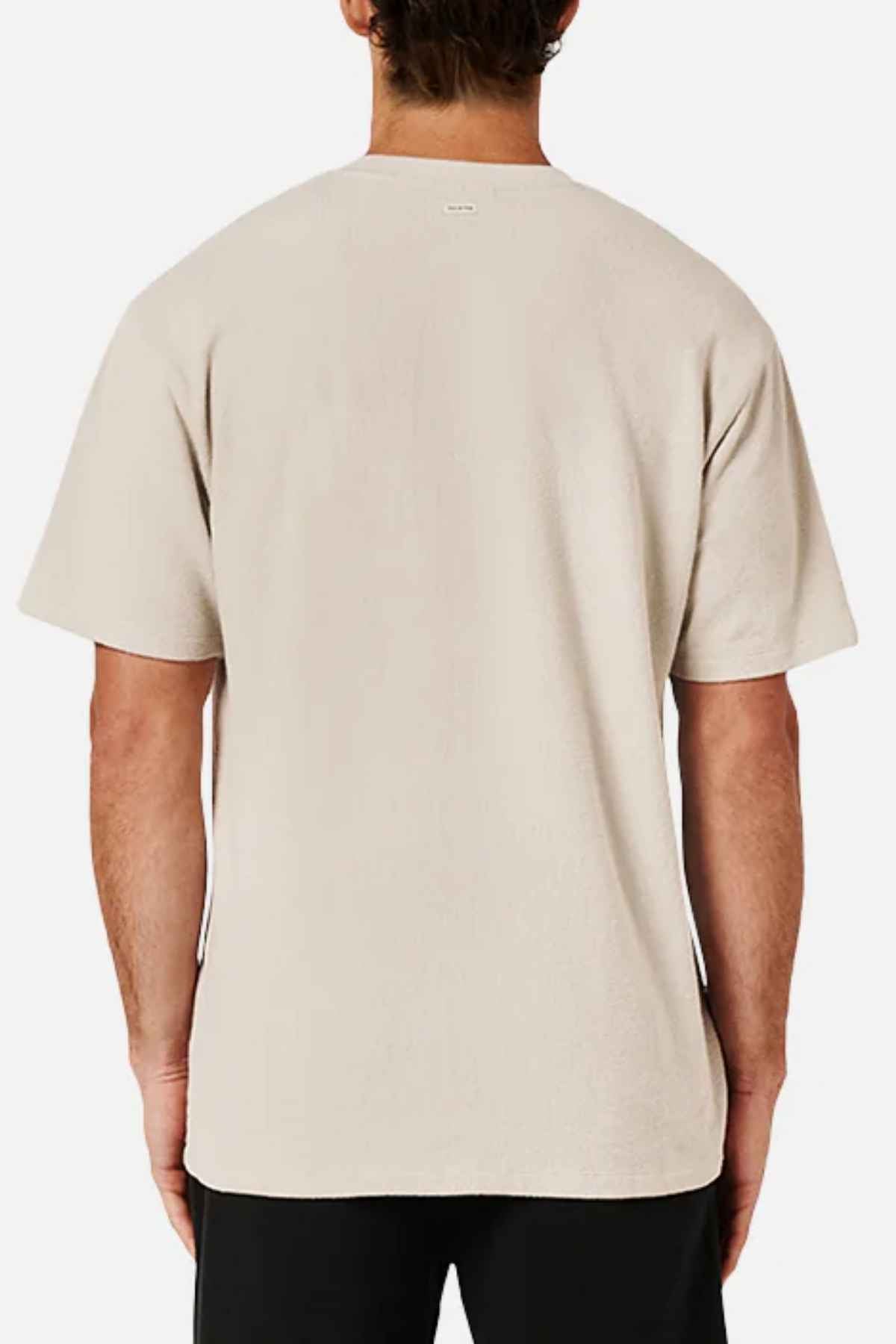 A person is seen from the back wearing an oversized look featuring the Industrie The Henderson Boucle Tee in beige paired with black pants. The plain, short-sleeved T-shirt is made from 100% cotton and set against a white background.