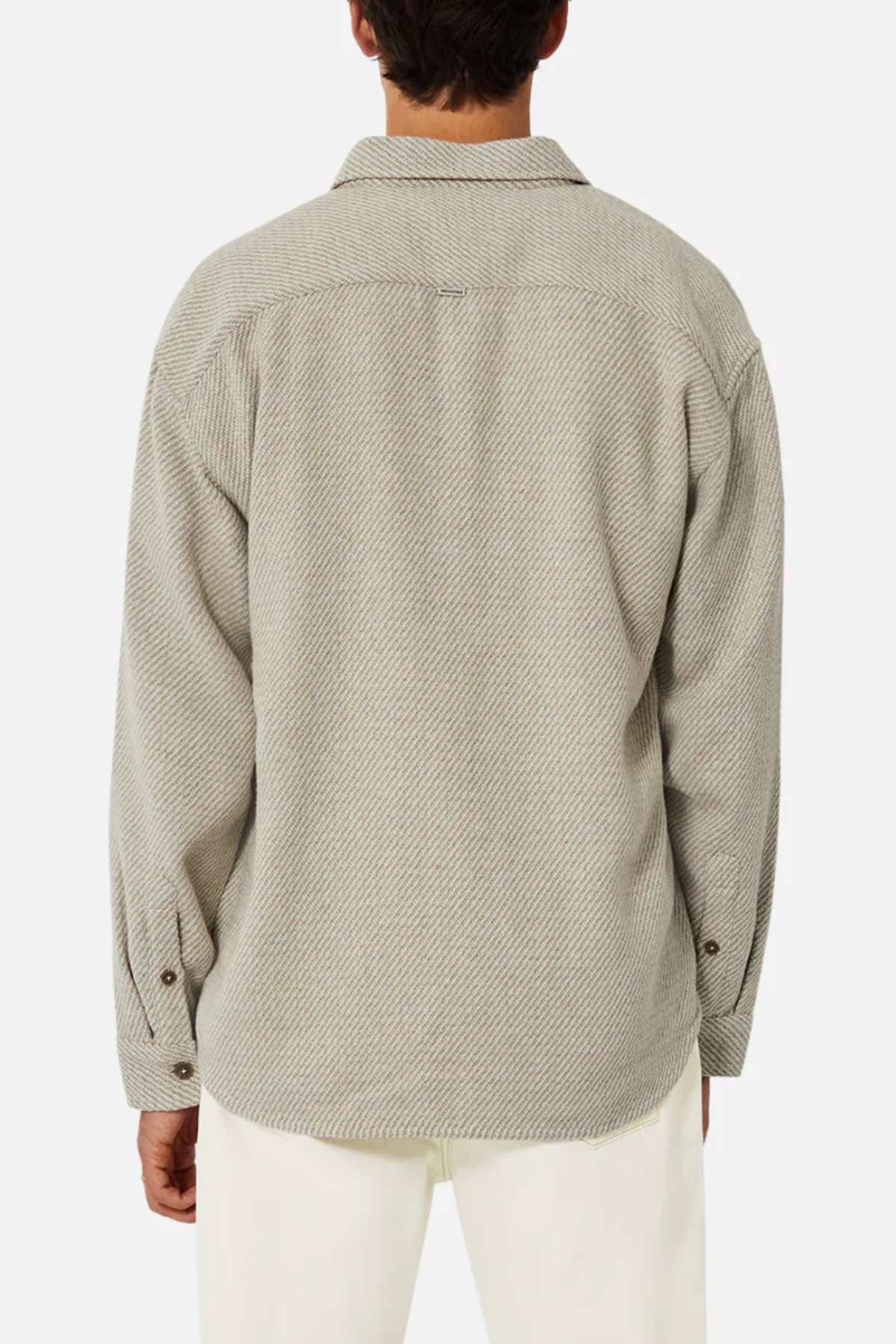 The individual is seen from the back wearing a light gray, relaxed-fit long-sleeved shirt with a subtle herringbone pattern. This is the Industrie The Jackson Shirt, complete with a collar and buttoned cuffs, paired stylishly with white pants against a plain white background.