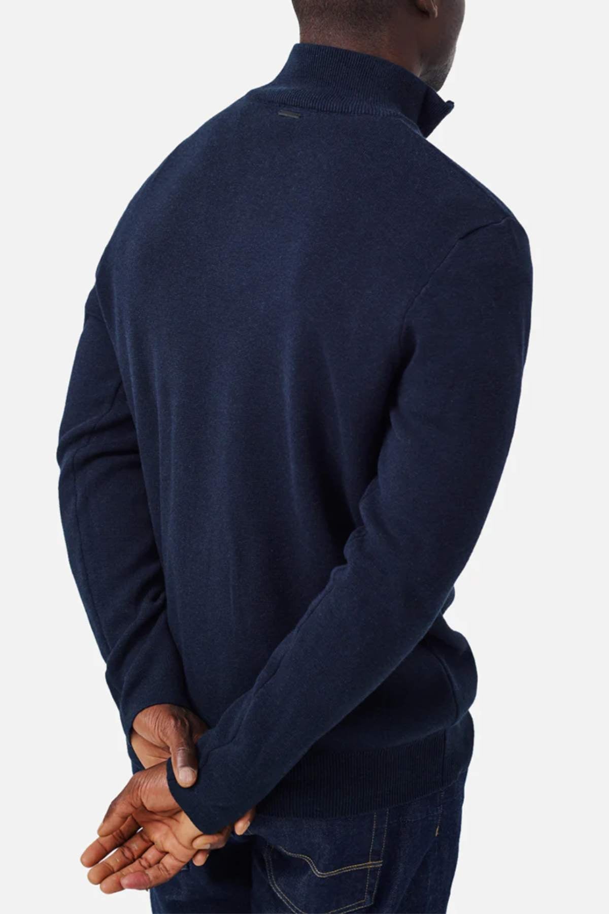 A person wearing the Industrie The Lakewood Zip Neck in dark blue, along with regular fit dark jeans, is shown from the back with their hands clasped behind them. Their head is turned slightly to the left against a plain white background.