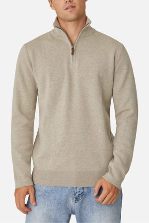 A person wears the Industrie The Lakewood Zip Neck sweater, light beige with a zip neck and regular fit, against a plain white background. The sweater is partially unzipped, and their hands rest by their sides.