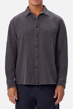 Someone wearing the Industrie Lisbon Long Sleeve Shirt—a dark gray, 100% cotton, textured long-sleeve button-up with classic collar and chest pocket—paired with dark pants, stands against a plain light background.