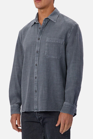 A person wearing the Industrie Lisbon Long Sleeve Shirt, made from 100% cotton with a chest pocket and classic collar, paired with dark jeans, stands against a plain light background.