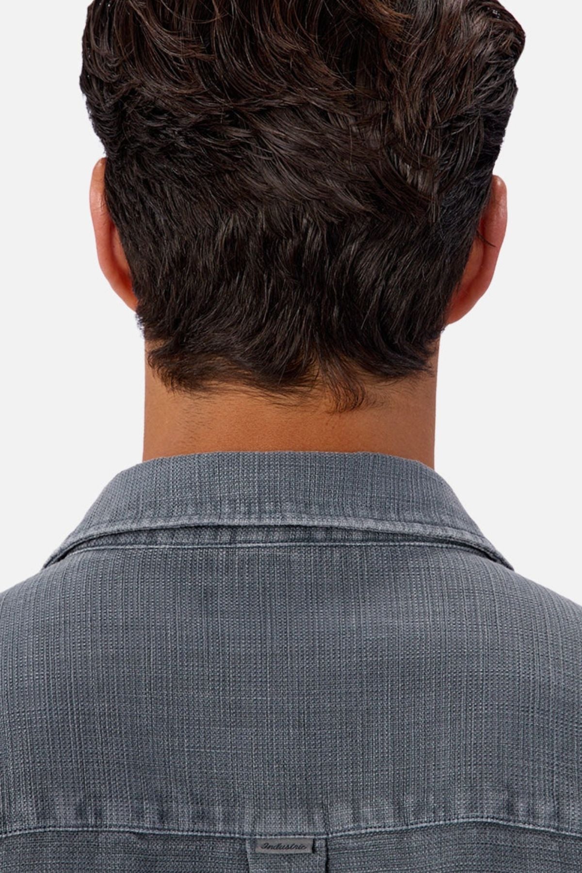 A person with short, dark brown hair is seen from behind wearing the Industrie Lisbon Long Sleeve Shirt, which features a textured gray fabric and classic collar, standing out against a plain, light-colored background.
