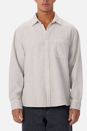 A person wears the Industrie Lisbon Long Sleeve Shirt in light gray, made from 100% cotton with a chest pocket and classic collar, untucked over dark pants against a plain background.