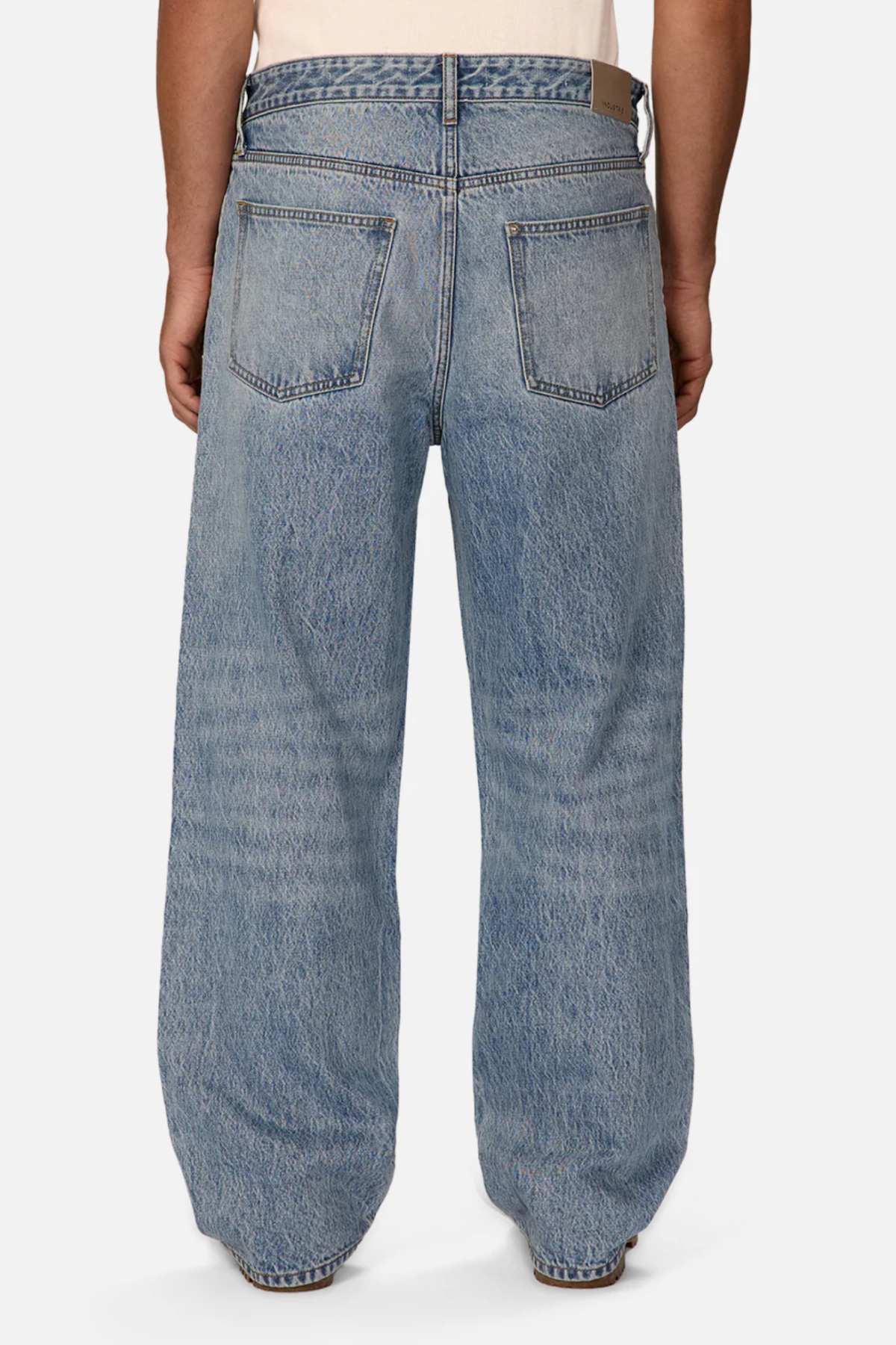A person wearing Industrie The Lone Star Jeans in light blue denim seen from the back against a plain white background. The jeans feature double stitching on the seams and have two back pockets. The individual is also wearing a light-colored shirt tucked into the jeans.