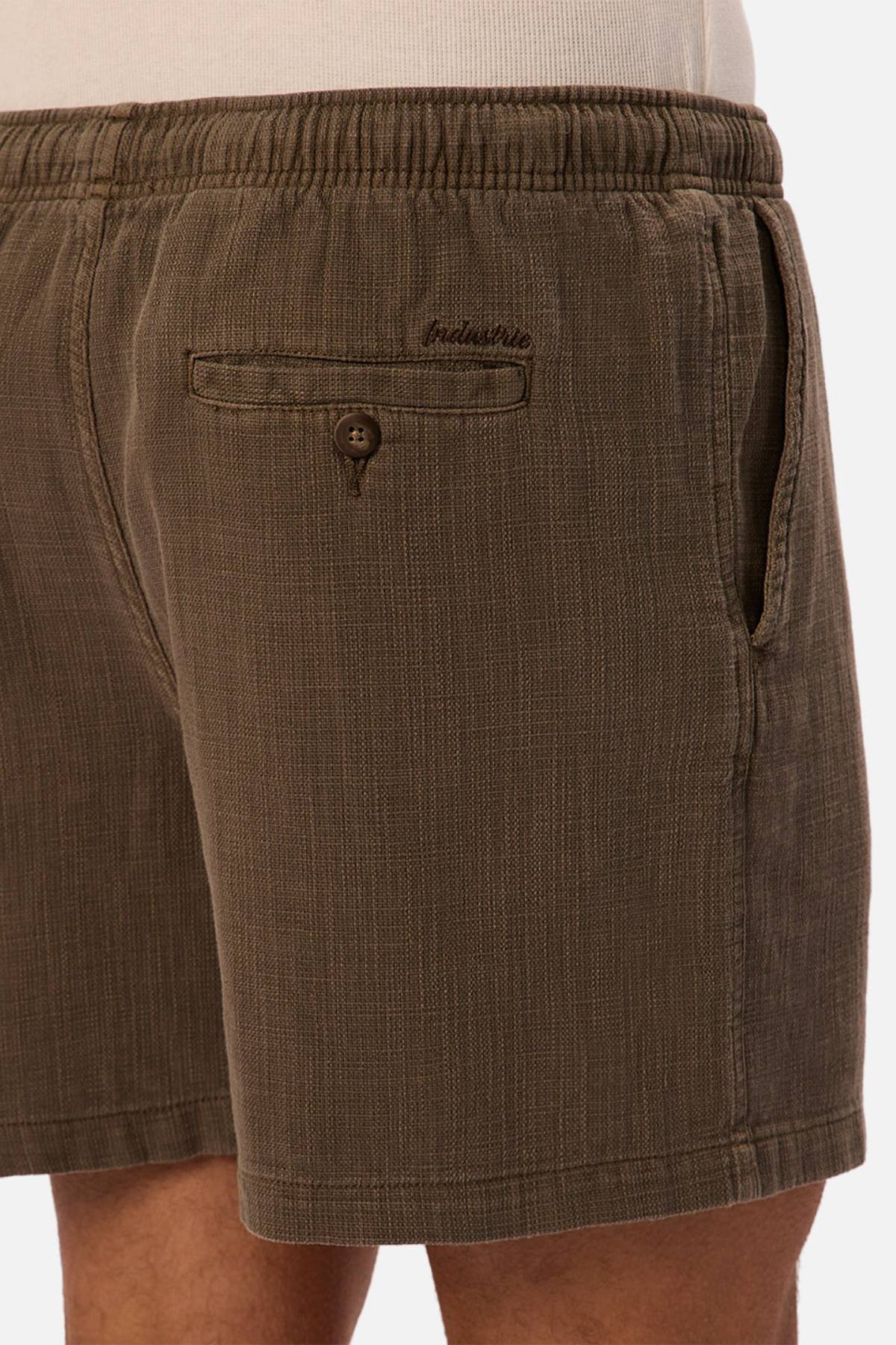Close-up of a person wearing Industrie The Mallorca Short, featuring lightweight textured fabric, elasticated waist, side pocket, buttoned back pocket, and "Industrie" embroidered above the back pocket.