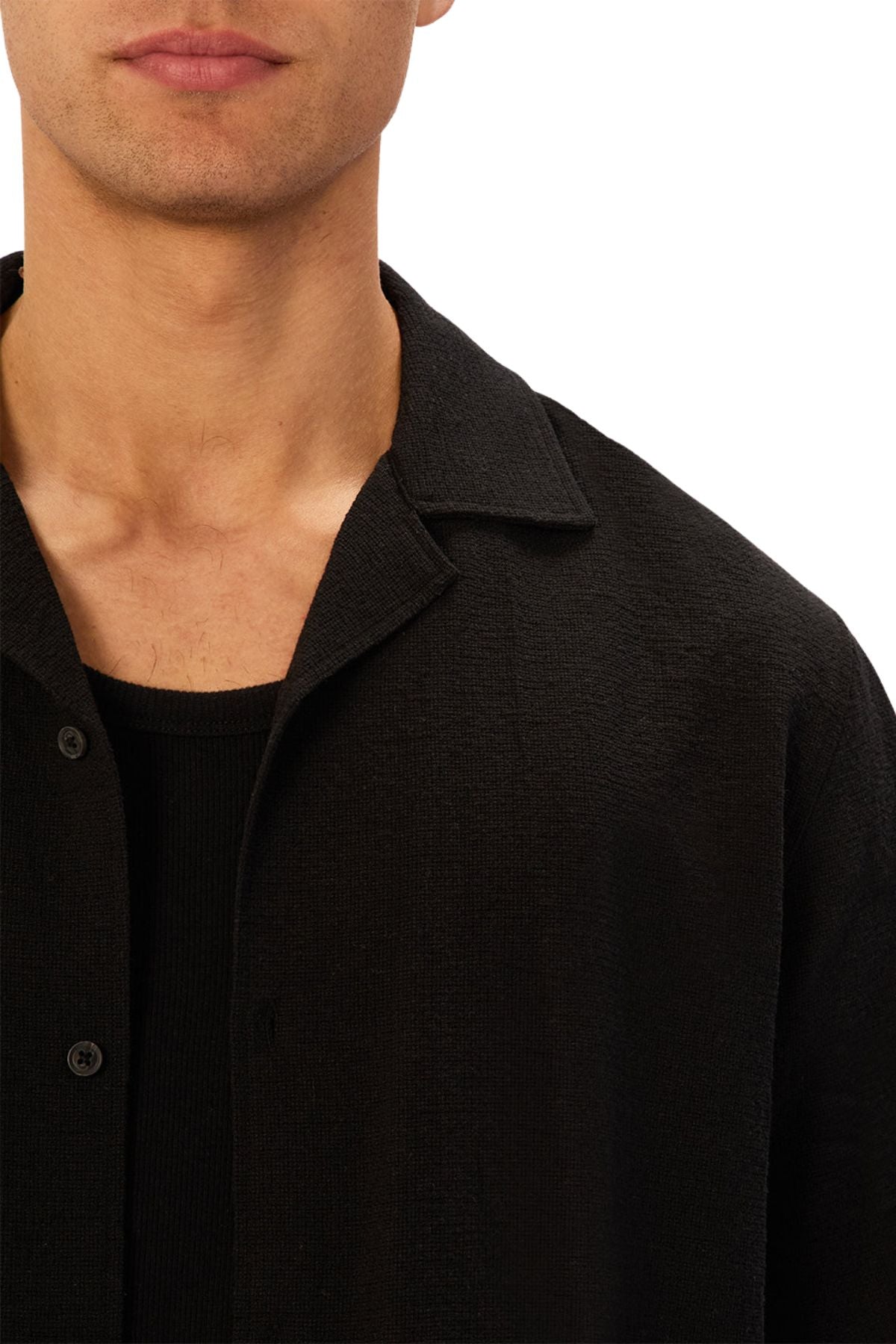 A man wears the Industrie The Marbella Short Sleeve Shirt, a black textured casual shirt layered over a black ribbed top. Shown from the shoulders up against a white background, only his mouth and chin are visible.