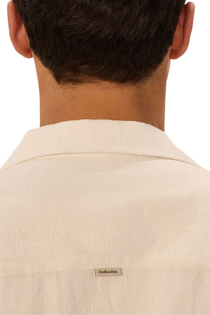 A close-up of the back of someone wearing the Industrie The Marbella Short Sleeve Shirt in textured white, with a small “Industrie” fabric label sewn on, showcases its relaxed fit and casual everyday style.
