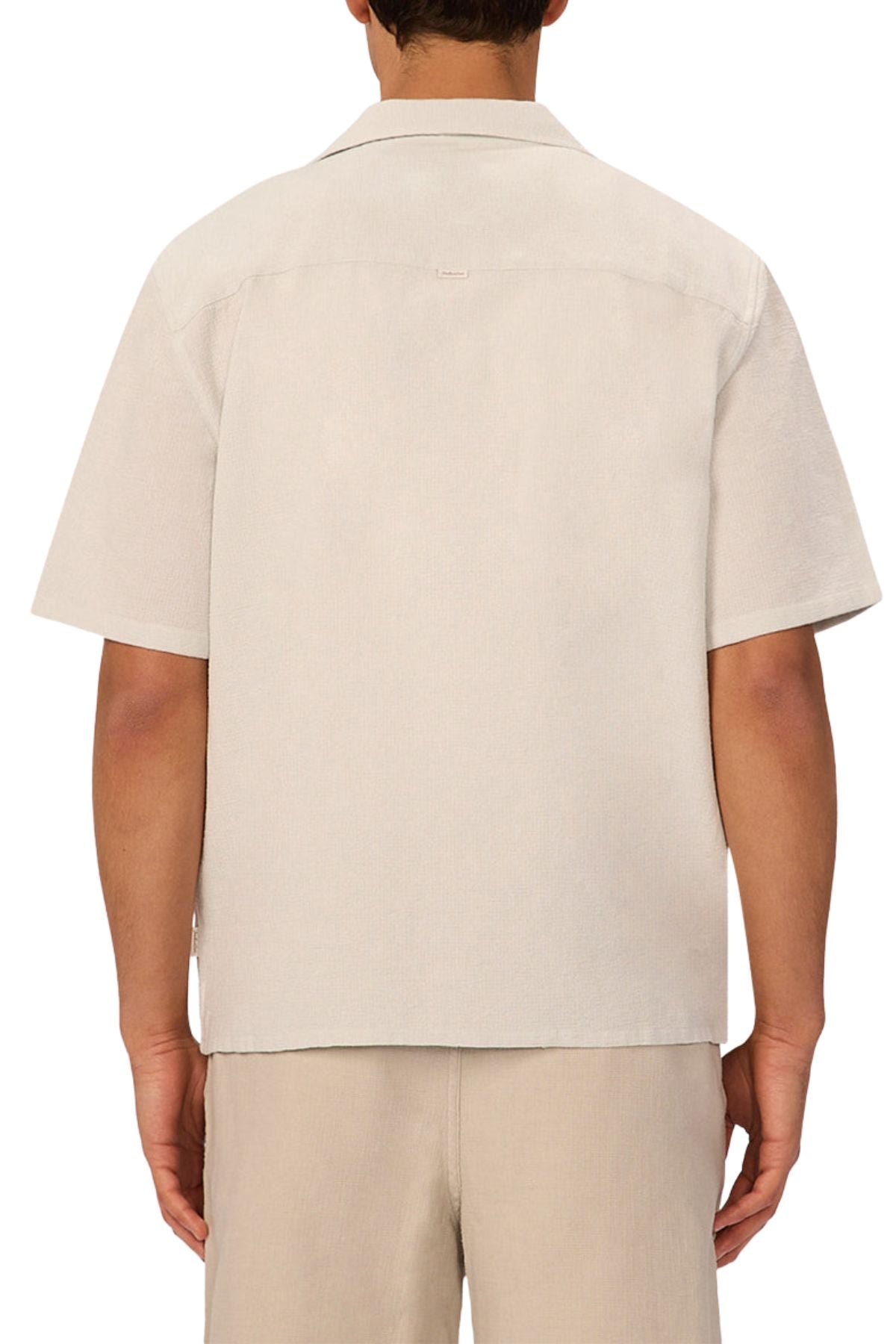 A person faces away, wearing the Industrie The Marbella Short Sleeve Shirt in a relaxed fit with matching beige shorts. The lightweight, textured shirt features a straight hem, set against a plain white background.