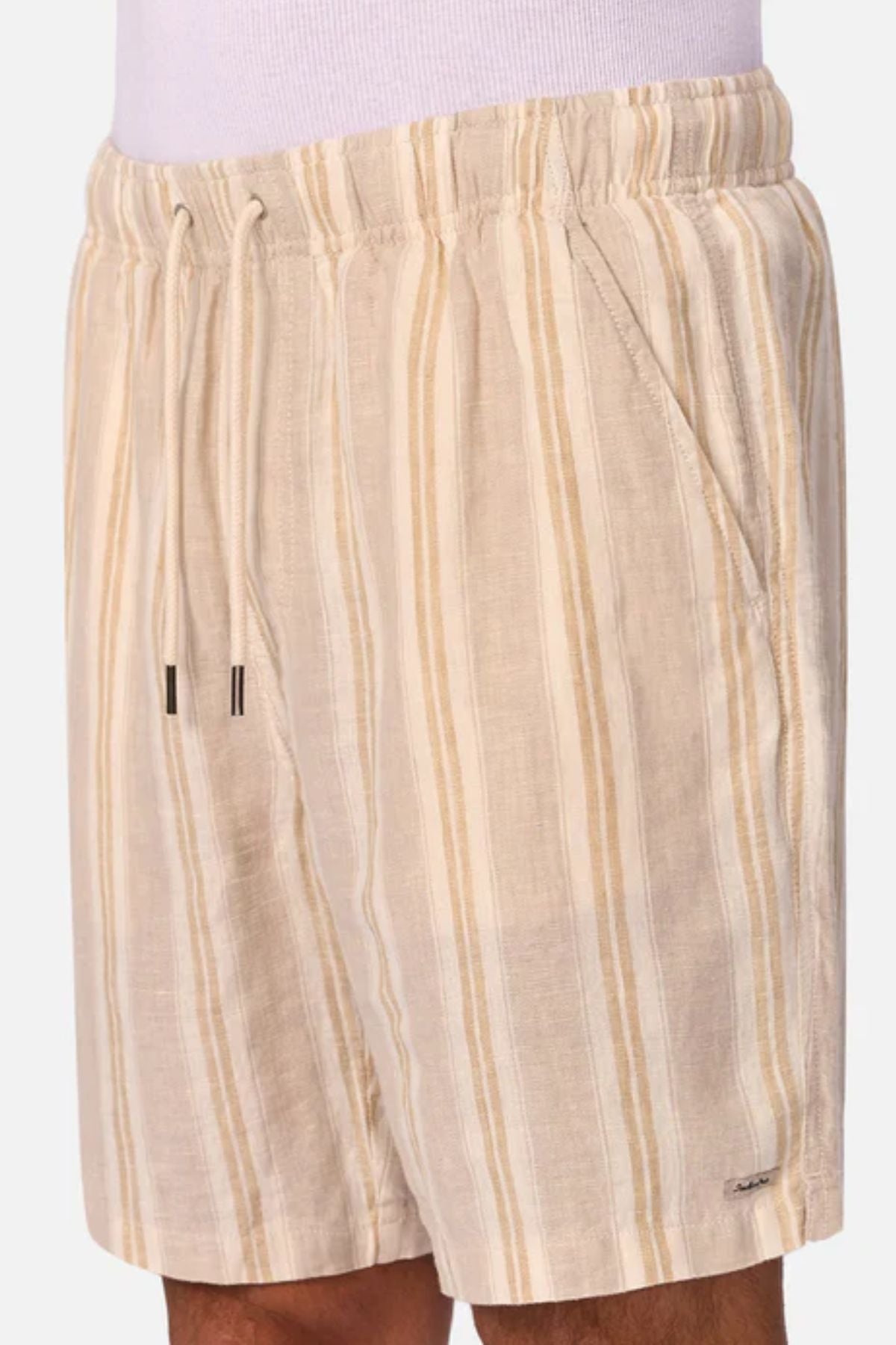 A person wears the Industrie The Matias Short—beige linen shorts with vertical cream and tan stripes, elastic waistband, drawstring, and side pockets. The breathable fabric is ideal for casual everyday wear.