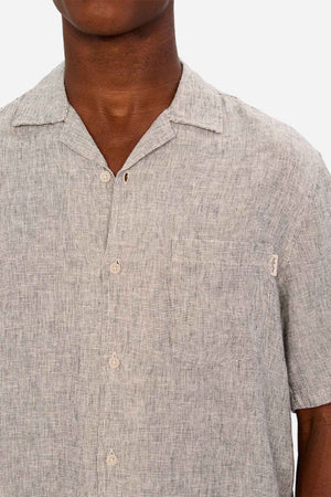 A person wearing the Industrie The Melrose Short Sleeve Shirt—a light gray, button-up linen Tencel shirt with a subtle texture, chest pocket, and relaxed collar. Only the upper torso and neck are shown.